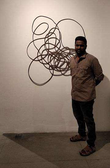 Kumaresan Selvaraj alongside his wall sculpture, 'It Ends Where it Starts'